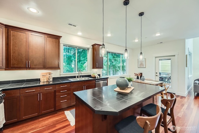 9064 177th Pl NE, Redmond, WA 98052 - kitchen with a breakfast bar, dishwasher, wood finished floors, dark countertops, and pendant lighting