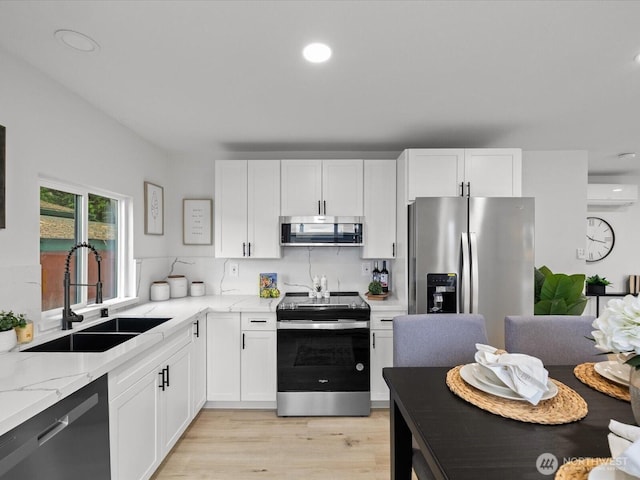 3704 Bells Ln, Langley, WA 98260 - kitchen with stainless steel appliances, an AC wall unit, light stone counters, white cabinets, and recessed lighting