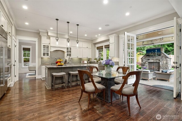 1709 223rd Ave SE, Sammamish, WA 98075 - dining room with dark wood-style flooring, healthy amount of natural light, a stone fireplace, recessed lighting, and crown molding