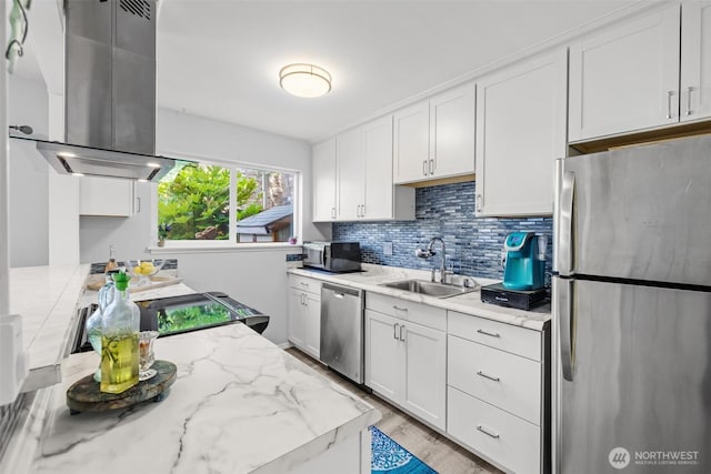 12240 SE 60th St Unit 41, Bellevue, WA 98006 - kitchen featuring appliances with stainless steel finishes, island exhaust hood, white cabinetry, backsplash, and light wood-style flooring