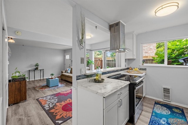 12240 SE 60th St Unit 41, Bellevue, WA 98006 - kitchen featuring stainless steel electric stove, island exhaust hood, light wood-type flooring, white cabinetry, and light stone counters