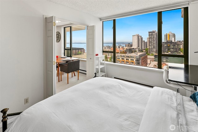 2201 3rd Ave Unit 1404, Seattle, WA 98121 - bedroom featuring a view of city, a textured ceiling, a baseboard radiator, and a baseboard heating unit