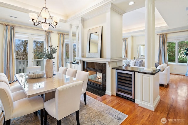 1510 38th Ave E, Seattle, WA 98112 - dining space featuring wine cooler, ornate columns, light wood-style floors, a raised ceiling, and crown molding