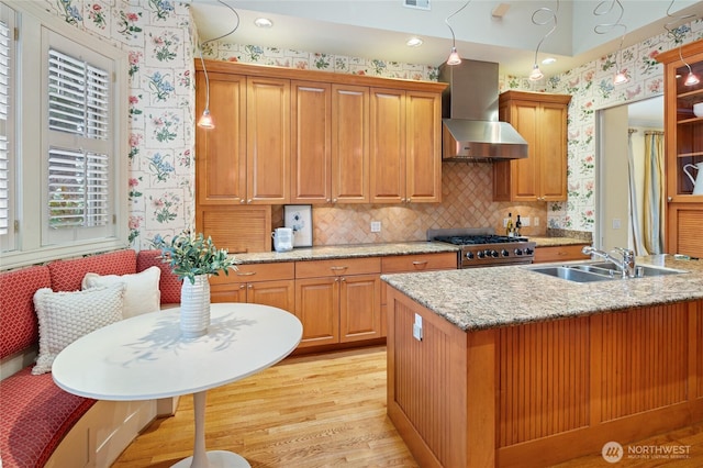 1510 38th Ave E, Seattle, WA 98112 - kitchen featuring wall chimney exhaust hood, wallpapered walls, light wood-type flooring, stove, and light stone countertops