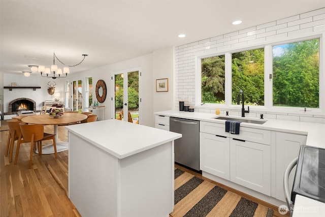 2534 Medina Cir, Medina, WA 98039 - kitchen with stainless steel dishwasher, range with electric stovetop, a center island, light wood-type flooring, and a brick fireplace