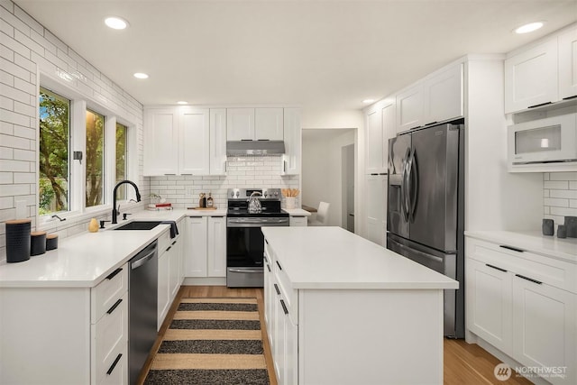 2534 Medina Cir, Medina, WA 98039 - kitchen featuring appliances with stainless steel finishes, under cabinet range hood, backsplash, a kitchen island, and recessed lighting