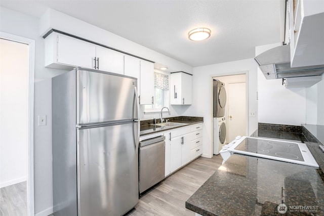 7233 S Sheridan, Tacoma, WA 98408 - kitchen featuring stainless steel appliances, estacked washer and dryer, exhaust hood, and white cabinets