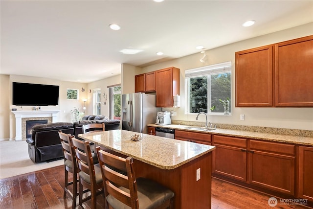 33908 12th Pl SW, Federal Way, WA 98023 - kitchen with appliances with stainless steel finishes, a kitchen island, a kitchen bar, a warm lit fireplace, and light stone counters