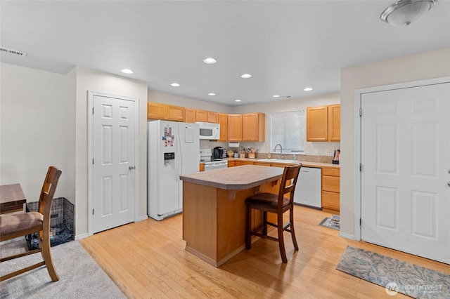 5468 Balustrade Blvd SE, Lacey, WA 98513 - kitchen featuring white appliances, a kitchen island, light wood-style flooring, a breakfast bar, and light brown cabinetry