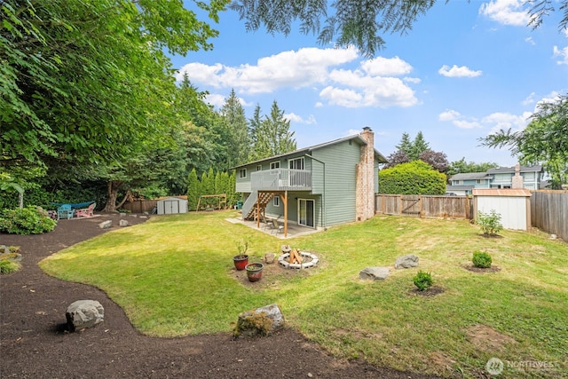 13402 60th Dr SE, Everett, WA 98208 - fenced backyard featuring a storage unit, stairway, an outdoor fire pit, a deck, and a patio area