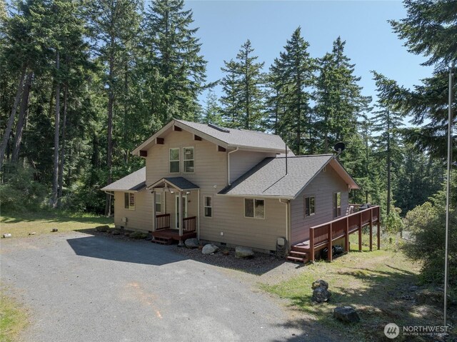 227 Bromley Dr, Orcas Island, WA 98245 - view of front of property featuring a shingled roof, driveway, a wooded view, and a wooden deck