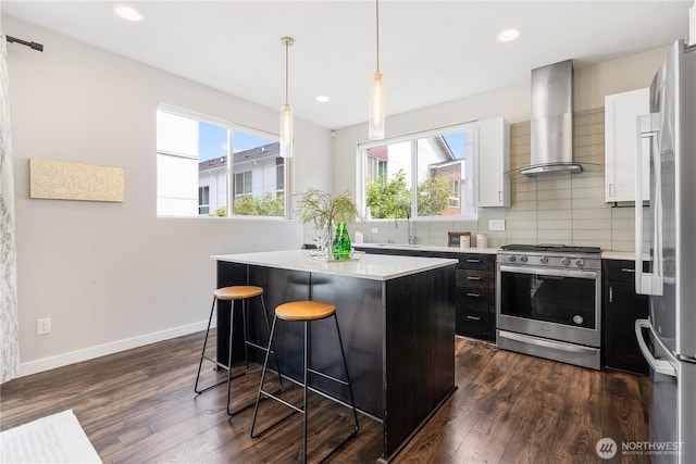 8600 21st Pl NE, Seattle, WA 98115 - kitchen featuring appliances with stainless steel finishes, wall chimney range hood, a kitchen island, a kitchen breakfast bar, and plenty of natural light