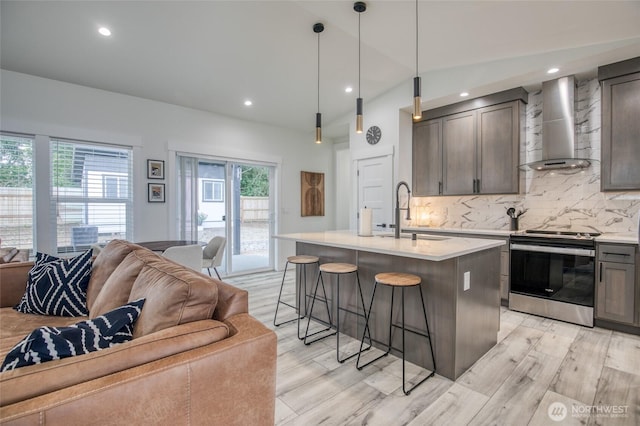 793 Island Cir SE, Ocean Shores, WA 98569 - kitchen with electric stove, wall chimney range hood, open floor plan, light countertops, and a kitchen breakfast bar