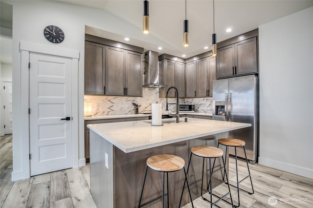 793 Island Cir SE, Ocean Shores, WA 98569 - kitchen featuring stainless steel fridge with ice dispenser, wall chimney range hood, dark brown cabinets, light wood finished floors, and light stone countertops