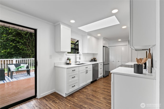 7411 201st St SW, Lynnwood, WA 98036 - kitchen with stainless steel appliances, a skylight, dark wood-style flooring, white cabinetry, and light countertops