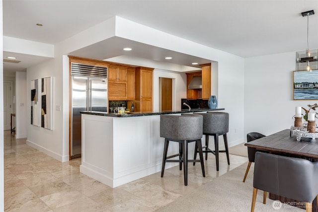 2015 SE Columbia River Dr Unit 320, Vancouver, WA 98661 - kitchen featuring stainless steel built in refrigerator, wall chimney range hood, recessed lighting, tasteful backsplash, and a peninsula
