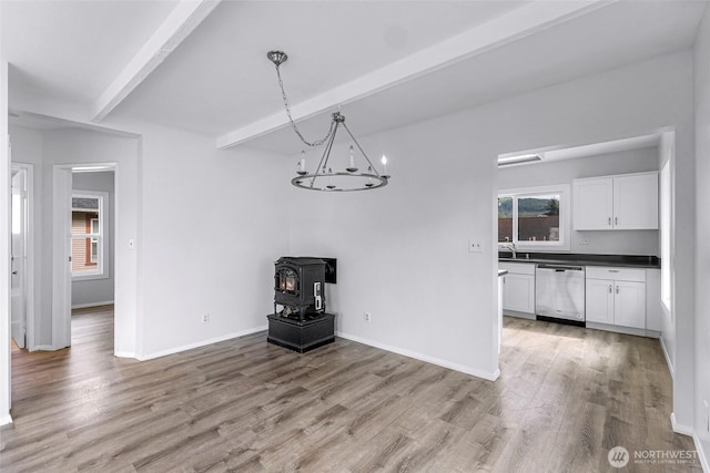 309 Bennett St, Sedro Woolley, WA 98284 - unfurnished dining area featuring beamed ceiling, a wood stove, light wood-style floors, and a chandelier
