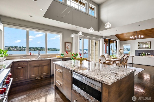 8440 Benotho Pl, Mercer Island, WA 98040 - kitchen featuring appliances with stainless steel finishes, dark wood-style flooring, light stone countertops, a kitchen island, and a chandelier