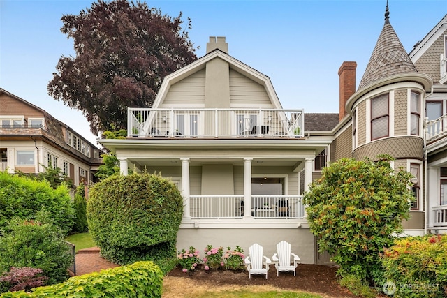 526 W Kinnear Pl, Seattle, WA 98119 - view of front facade featuring a balcony, a chimney, covered porch, and a gambrel roof