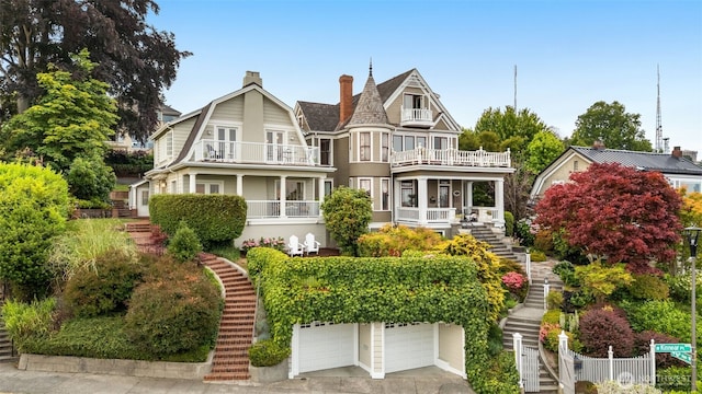 526 W Kinnear Pl, Seattle, WA 98119 - victorian house featuring stairway, a balcony, a garage, a gambrel roof, and a chimney