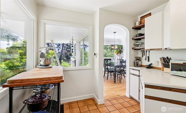 5325 Monta Vista Dr E, Edgewood, WA 98372 - kitchen with open shelves, white cabinetry, light countertops, light tile patterned floors, and arched walkways