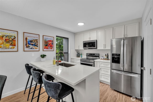 11701 100th Ave NE Unit 2, Kirkland, WA 98034 - kitchen featuring appliances with stainless steel finishes, a kitchen bar, light wood-style floors, and light countertops