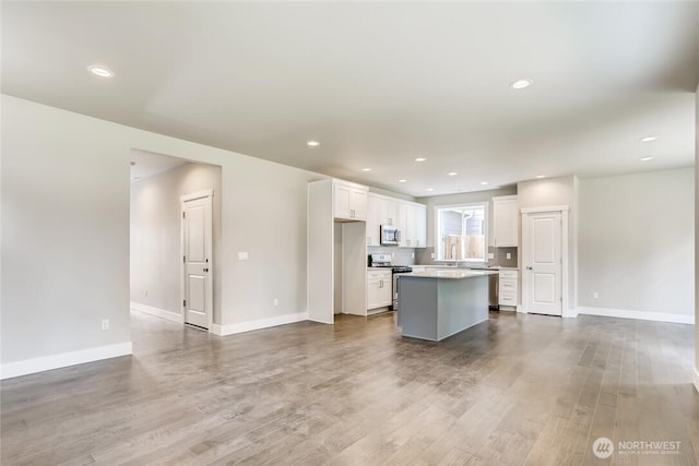 411 205th St SW Unit A, Lynnwood, WA 98036 - kitchen with appliances with stainless steel finishes, a kitchen island, white cabinetry, wood finished floors, and open floor plan