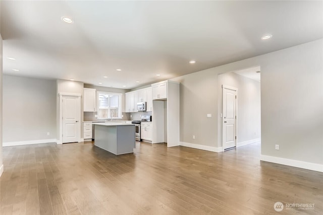 411 205th St SW Unit A, Lynnwood, WA 98036 - kitchen featuring appliances with stainless steel finishes, white cabinets, a kitchen island, wood finished floors, and open floor plan