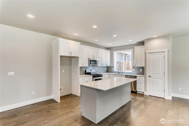 411 205th St SW Unit A, Lynnwood, WA 98036 - kitchen featuring appliances with stainless steel finishes, white cabinetry, hardwood / wood-style flooring, light countertops, and a center island