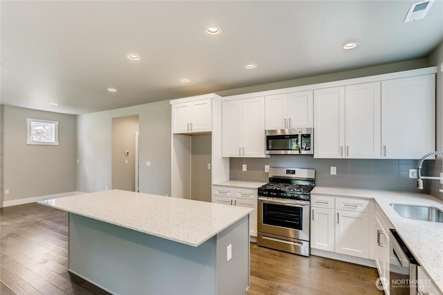 411 205th St SW Unit A, Lynnwood, WA 98036 - kitchen featuring appliances with stainless steel finishes, wood-type flooring, light stone counters, a kitchen island, and white cabinets