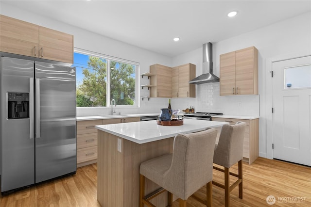 9228 21st Ave SW, Seattle, WA 98106 - kitchen featuring stainless steel fridge, wall chimney range hood, light brown cabinets, and recessed lighting