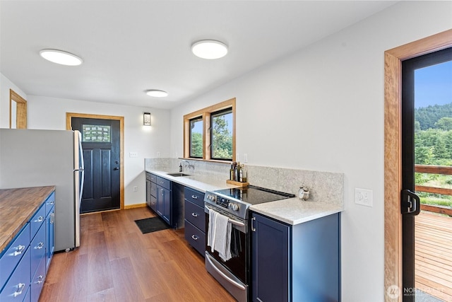 13402 Spring Site Rd E, Orting, WA 98360 - kitchen with appliances with stainless steel finishes, blue cabinetry, wood finished floors, and healthy amount of natural light