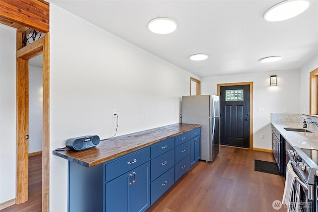 13402 Spring Site Rd E, Orting, WA 98360 - kitchen with stainless steel appliances, blue cabinetry, dark wood finished floors, and wood counters