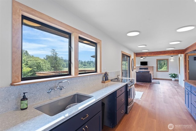 13402 Spring Site Rd E, Orting, WA 98360 - kitchen featuring stainless steel range with electric cooktop, light wood finished floors, light stone counters, backsplash, and a fireplace