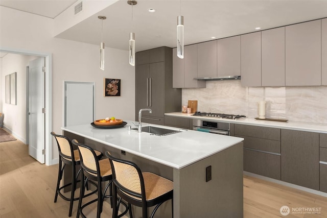2510 6th Ave Unit 3605, Seattle, WA 98121 - kitchen featuring appliances with stainless steel finishes, light wood-style floors, tasteful backsplash, and a breakfast bar area