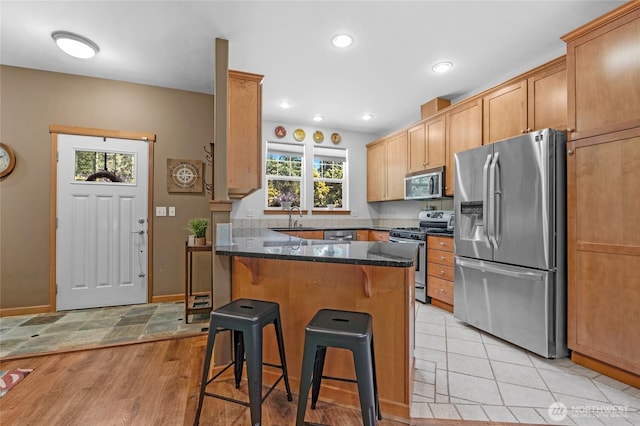 17356 Red Hawk Ct, Mount Vernon, WA 98274 - kitchen featuring appliances with stainless steel finishes, a breakfast bar area, dark stone countertops, a peninsula, and light wood finished floors