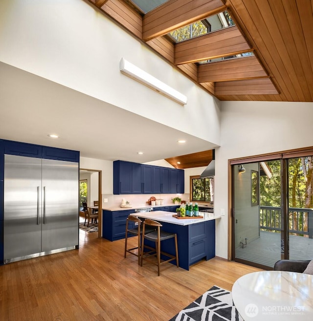 6160 W Mercer Way, Mercer Island, WA 98040 - kitchen with blue cabinets, light countertops, a breakfast bar area, light wood-style floors, and high vaulted ceiling