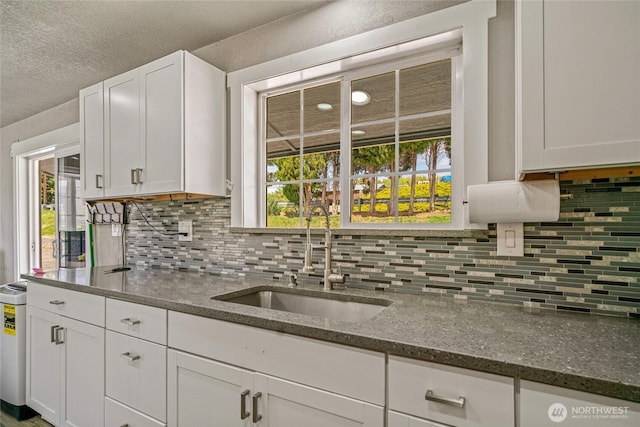 2440 Rock Island Rd, East Wenatchee, WA 98802 - kitchen featuring white cabinets, decorative backsplash, dark stone countertops, and a textured ceiling