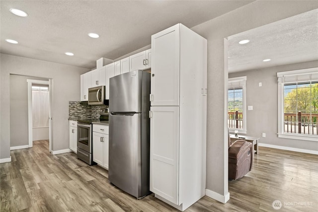 2440 Rock Island Rd, East Wenatchee, WA 98802 - kitchen featuring stainless steel appliances, wood finished floors, recessed lighting, white cabinets, and a textured ceiling