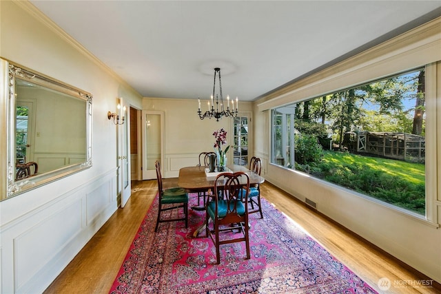 2425 Evergreen Point Rd, Medina, WA 98039 - dining area with wood finished floors, healthy amount of natural light, a chandelier, crown molding, and wainscoting