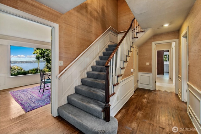 2425 Evergreen Point Rd, Medina, WA 98039 - staircase with wood finished floors, healthy amount of natural light, a wainscoted wall, and a water view