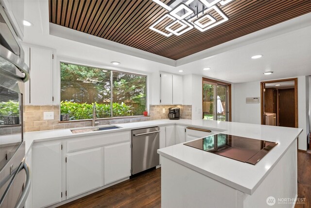 13222 76th Avenue Ct E, Puyallup, WA 98373 - kitchen featuring appliances with stainless steel finishes, dark wood-style floors, backsplash, a peninsula, and a raised ceiling