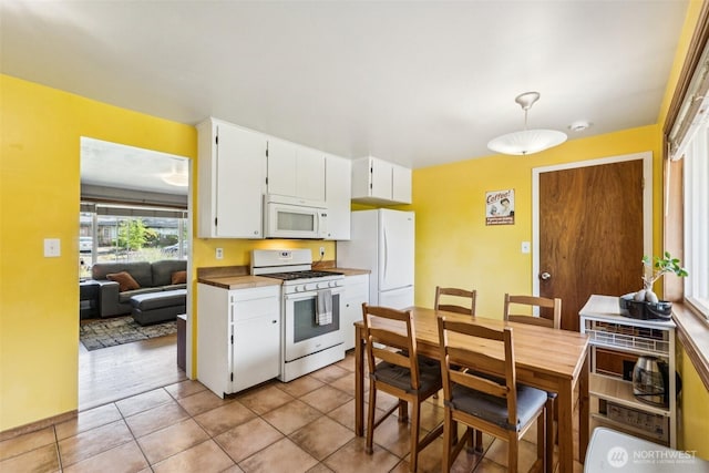 1921 Mountain View Dr, Mount Vernon, WA 98273 - kitchen with white appliances, white cabinetry, light tile patterned floors, hanging light fixtures, and light countertops
