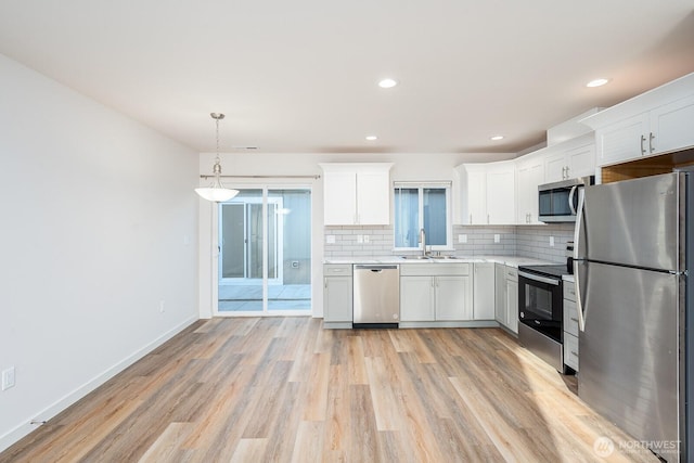 1325 Shaw St, Moses Lake, WA 98837 - kitchen featuring stainless steel appliances, light countertops, decorative backsplash, light wood-style flooring, and white cabinets