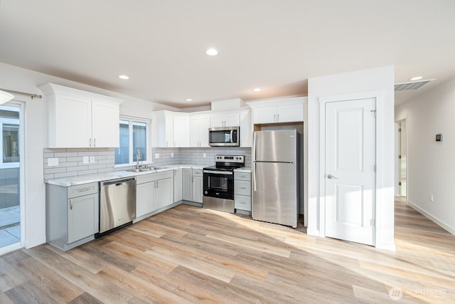 1325 Shaw St, Moses Lake, WA 98837 - kitchen featuring stainless steel appliances, light wood-style floors, tasteful backsplash, white cabinetry, and recessed lighting