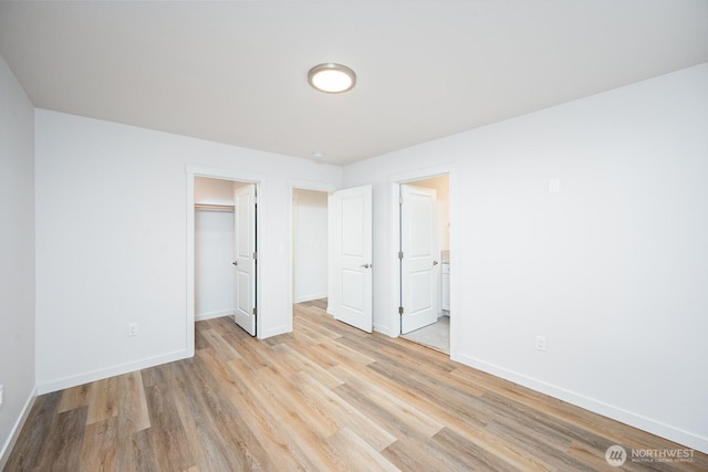 1325 Shaw St, Moses Lake, WA 98837 - unfurnished bedroom with light wood-type flooring, a walk in closet, a closet, and connected bathroom