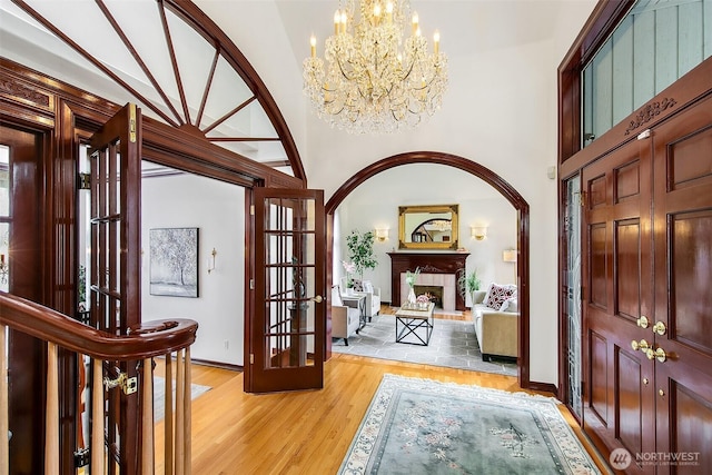 21031 49th Ave SE, Bothell, WA 98021 - entrance foyer featuring a chandelier, light wood-style floors, a fireplace with raised hearth, a towering ceiling, and french doors