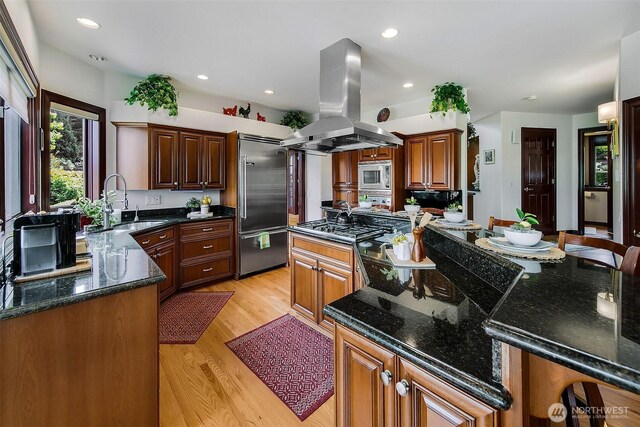 21031 49th Ave SE, Bothell, WA 98021 - kitchen featuring island range hood, built in appliances, a center island, light wood finished floors, and dark stone countertops