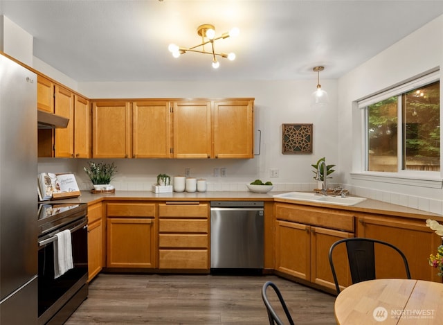 10307 140th Street Ct E Unit 3, Puyallup, WA 98374 - kitchen featuring appliances with stainless steel finishes, under cabinet range hood, wood finished floors, light countertops, and pendant lighting
