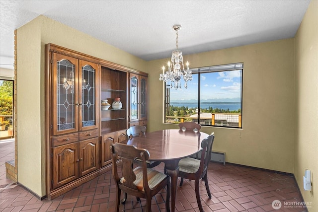 1125 Vista Pl, Edmonds, WA 98020 - dining area featuring a chandelier, brick patterned flooring, and a textured ceiling